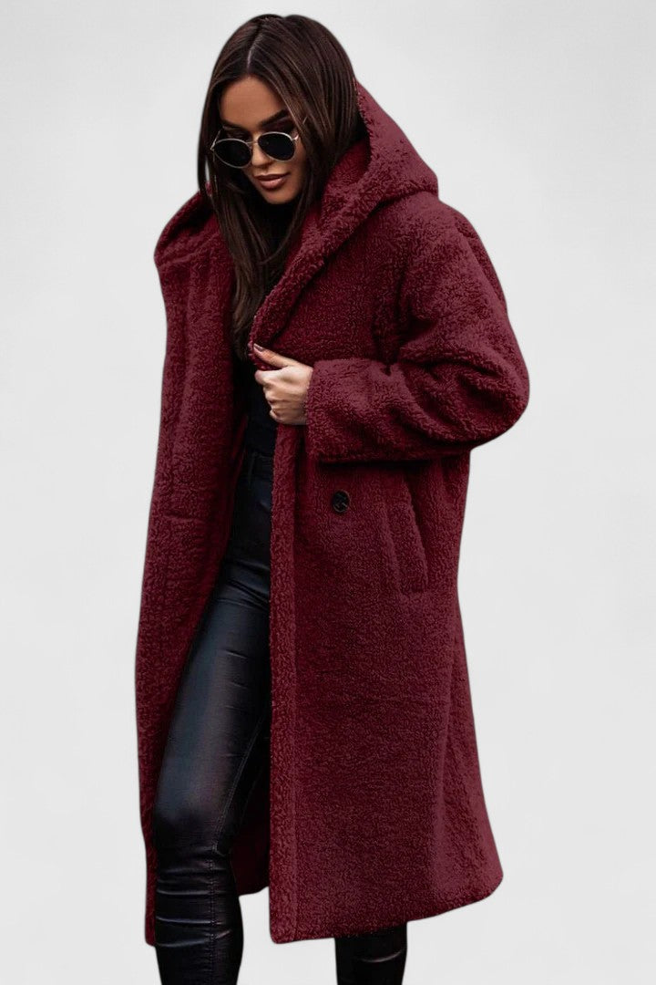 A woman wearing a long, softly textured hooded winter coat with an open front