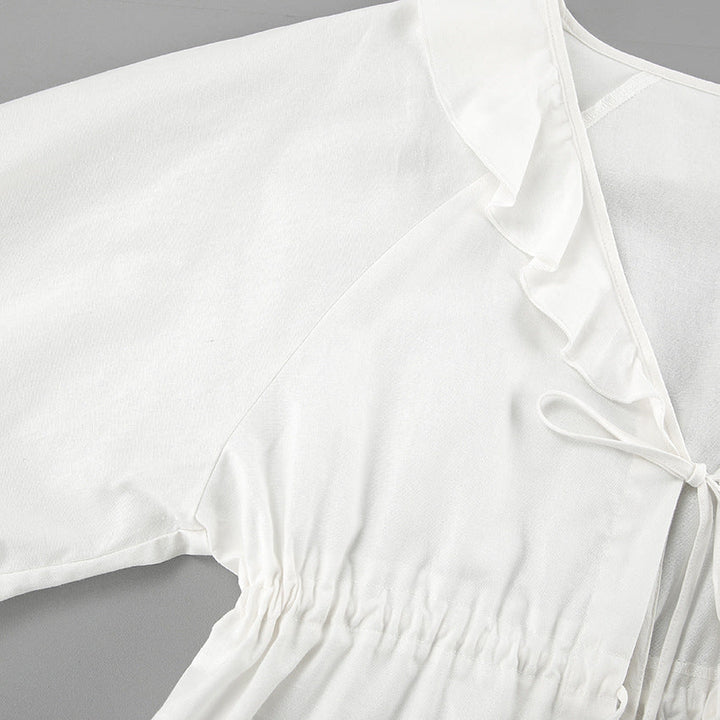 A woman wearing a white ruffle top with matching shorts and a tie waist
