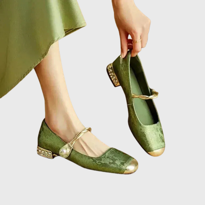 A woman wearing green low-heel Mary Janes with a twisted gold strap, gilded cap toe and a crystal-set heel
