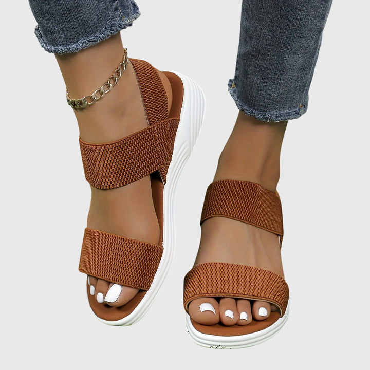 Black open-toe everyday sandals with wide stretch straps and a thick cushioned sole.