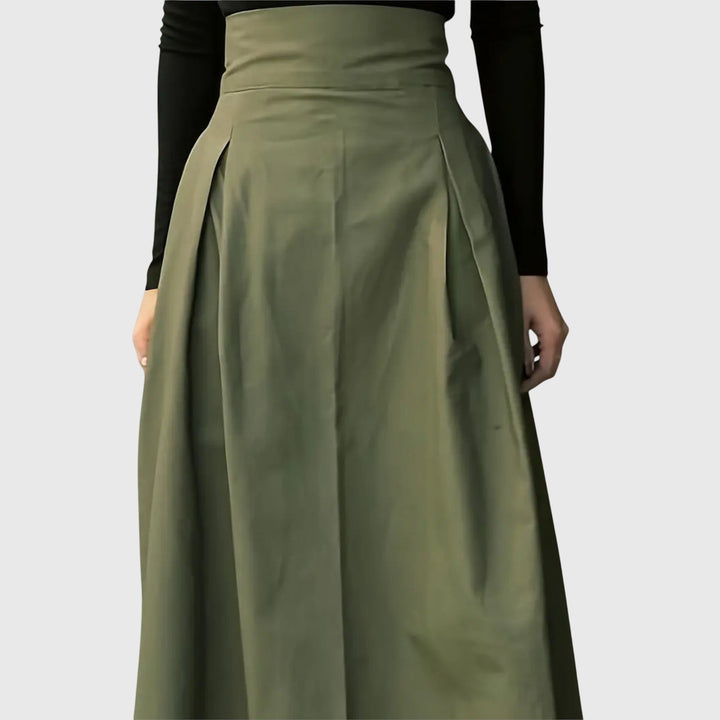 A woman wearing a flared green midi skirt with a belt detail at the waist.