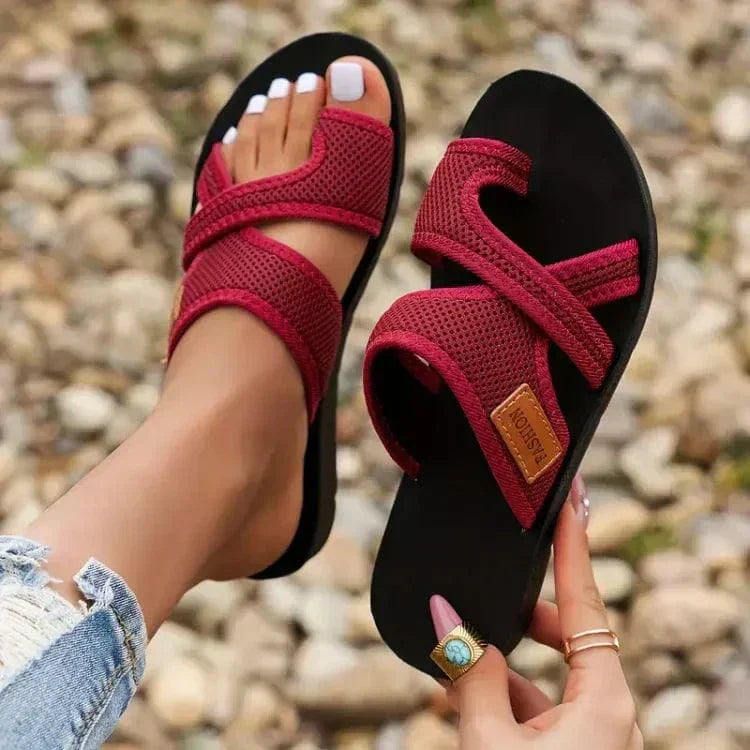 A woman on a summer walk wearing red comfort sandals with a broad, cushioned footbed.