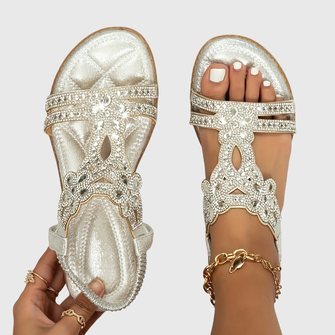 A woman wearing sky blue jewelled sandals with sparkling stones across the straps and a stretchy slingback.