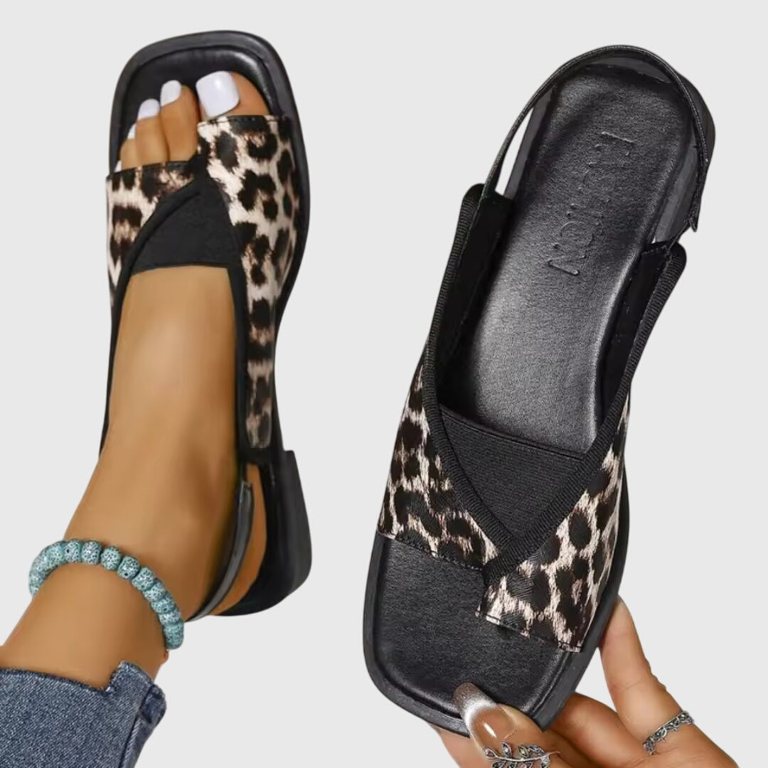 A woman wearing bold two-tone slide sandals on a warm city break.