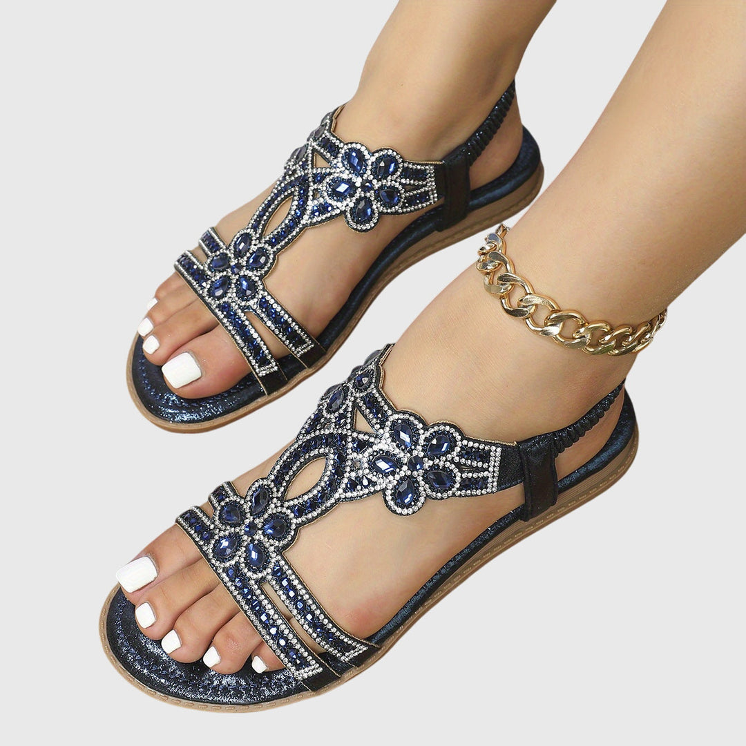 A woman wearing sky blue jewelled sandals with sparkling stones across the straps and a stretchy slingback.