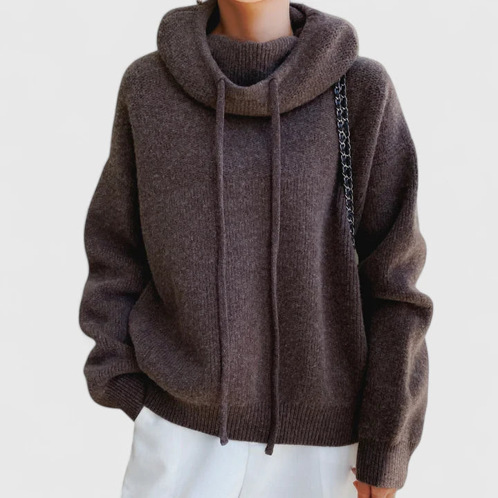 A woman wearing a cosy soft green hoodie with a drawstring hood and white pants.