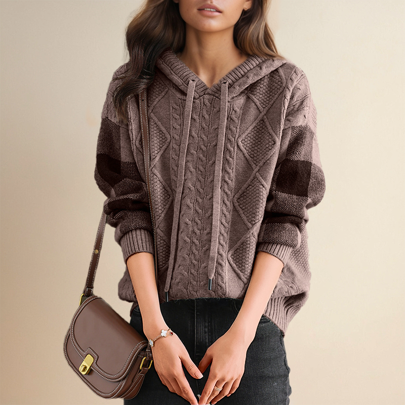 A woman wearing a soft cable-textured hooded sweater, cosy and warm with the hood down.