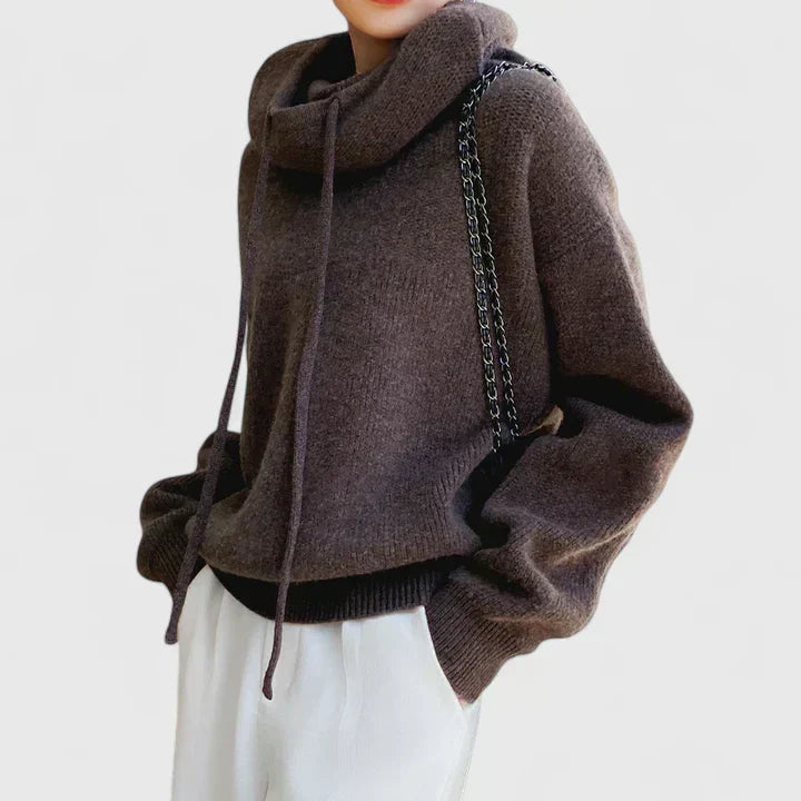 A woman wearing a cosy soft green hoodie with a drawstring hood and white pants.