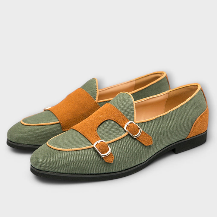 A woman wearing cream and tan round-toe slip-on loafers with twin gold buckle straps, walking with ease.