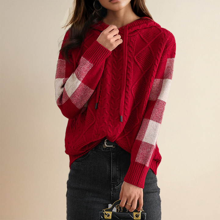 A woman wearing a soft cable-textured hooded sweater, cosy and warm with the hood down.