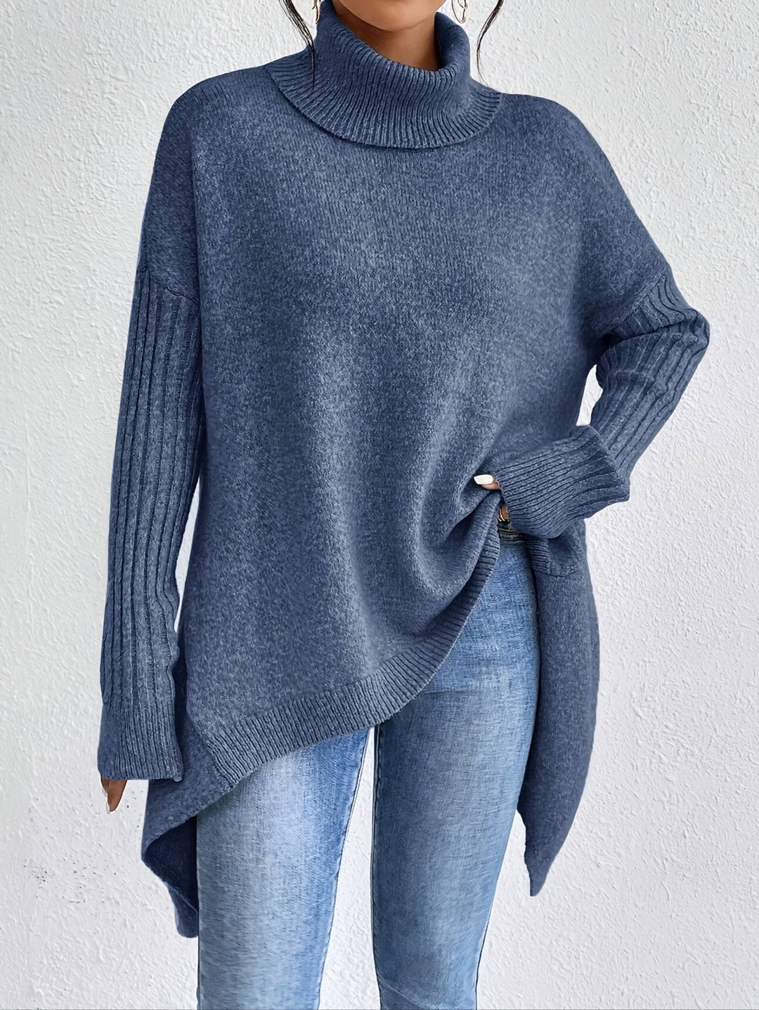 A woman wearing a stand-collar sweater with a chic asymmetric drape, warm and polished.
