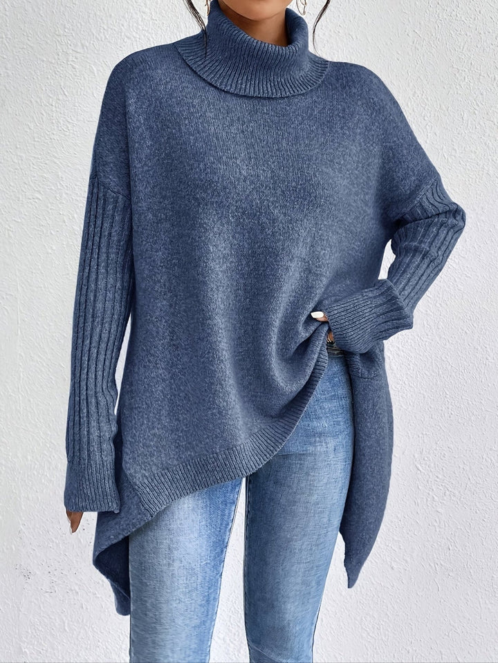A woman wearing a stand-collar sweater with a chic asymmetric drape, warm and polished.