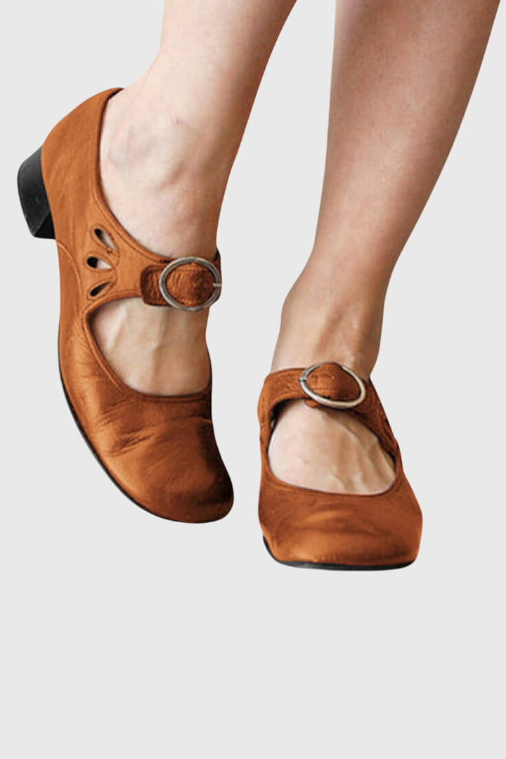 A woman wearing low heel Mary Janes with an adjustable strap, dressed for work.