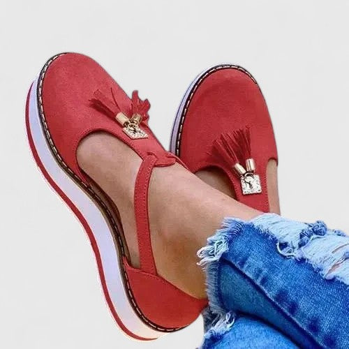 A woman wearing elegant supportive loafers with golden detail and tailored pants, looking polished and at ease.