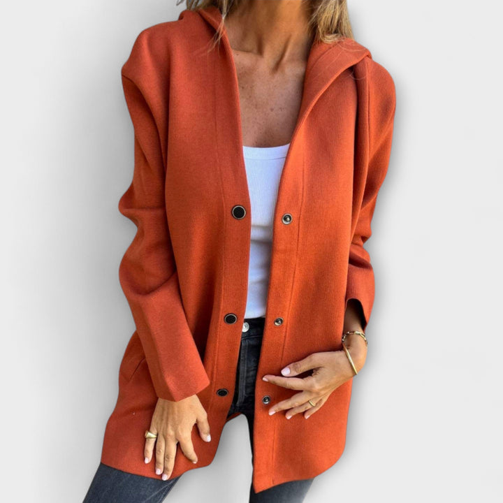 A woman wearing a relaxed longline hooded jacket with a button-through front over jeans.