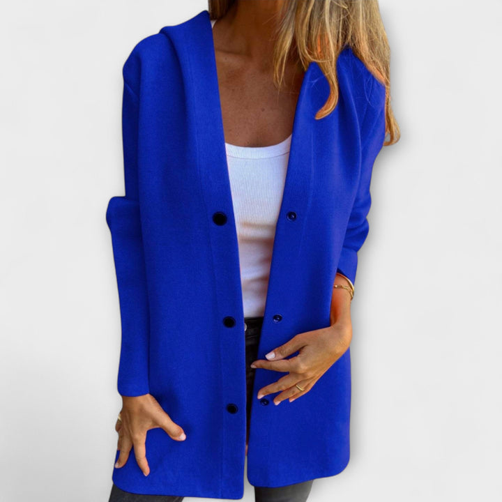 A woman wearing a relaxed longline hooded jacket with a button-through front over jeans.