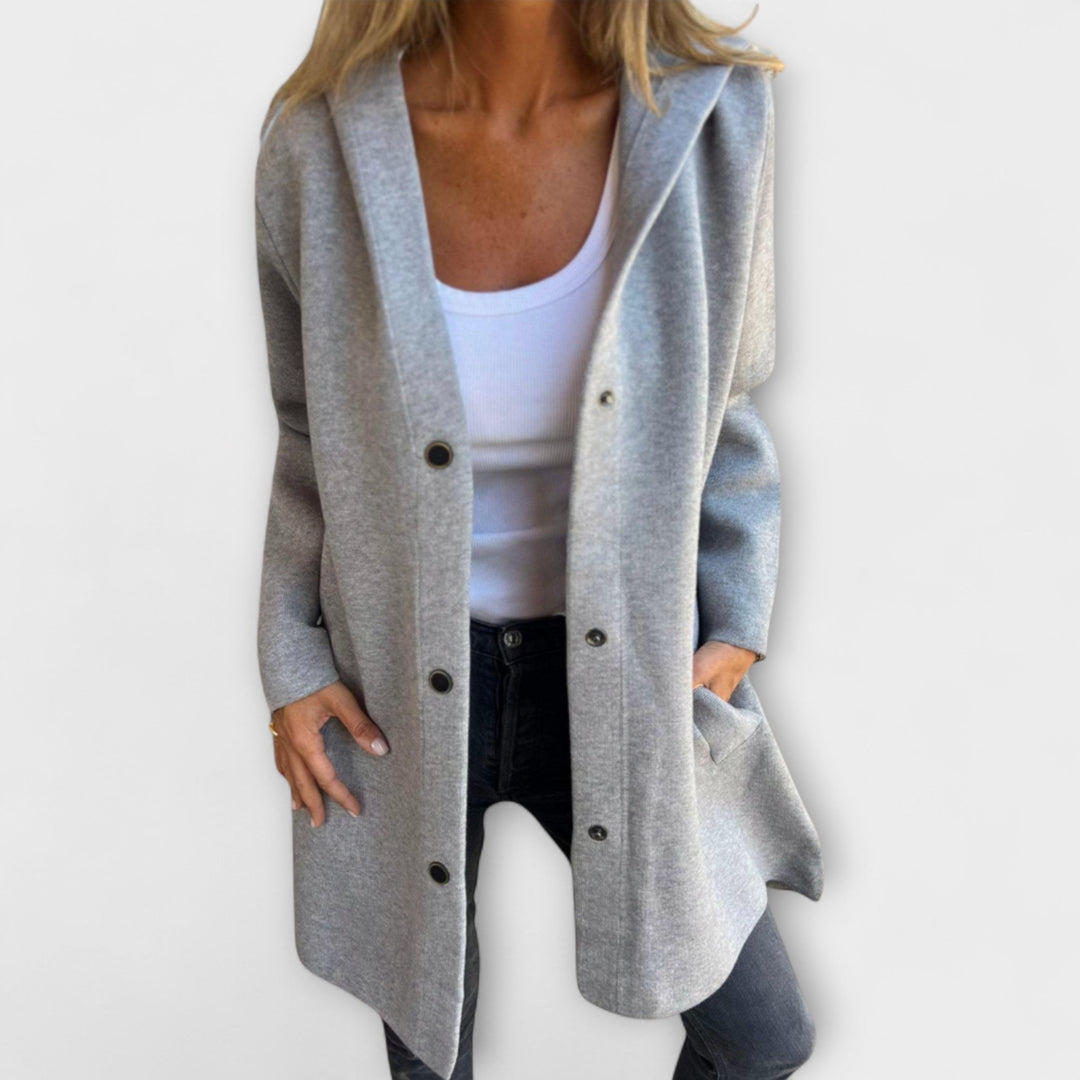 A woman wearing a relaxed longline hooded jacket with a button-through front over jeans.