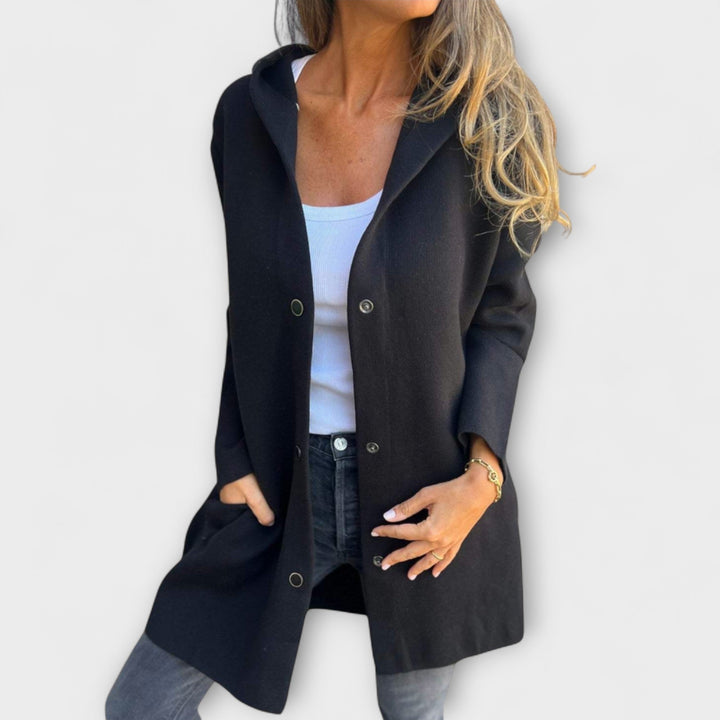 A woman wearing a relaxed longline hooded jacket with a button-through front over jeans.