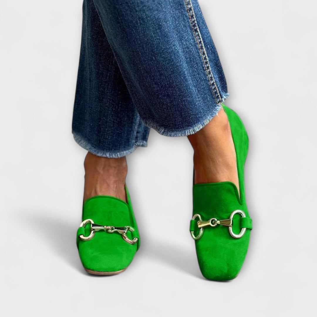 A woman wearing green slip-on loafers with a gold horsebit detail, dressed for a special afternoon.