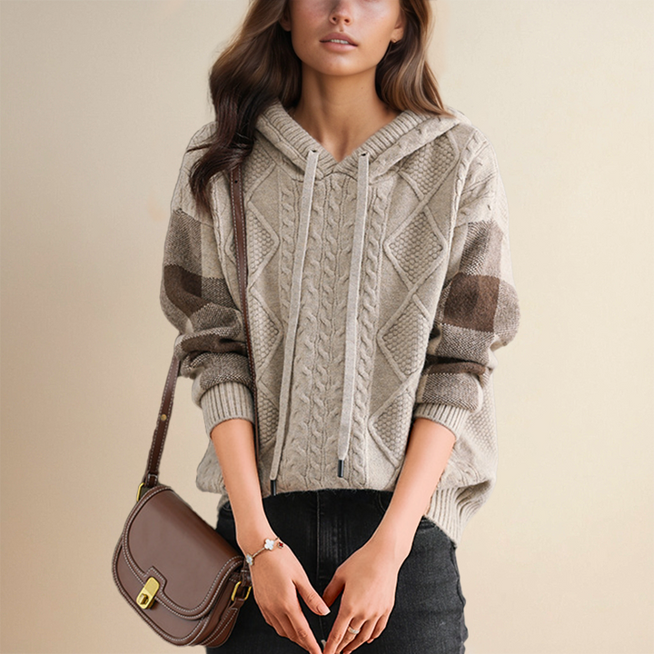A woman wearing a soft cable-textured hooded sweater, cosy and warm with the hood down.