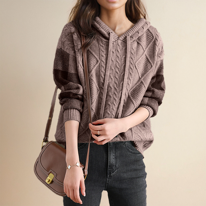 A woman wearing a soft cable-textured hooded sweater, cosy and warm with the hood down.