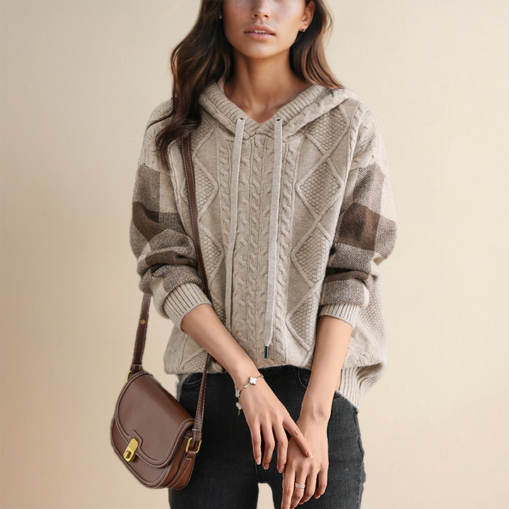 A woman wearing a soft cable-textured hooded sweater, cosy and warm with the hood down.