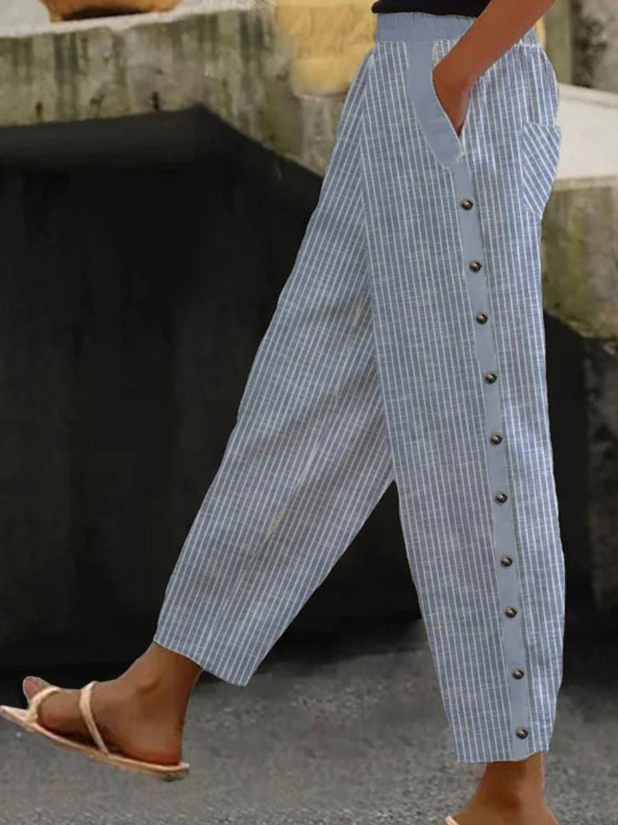 A woman wearing striped pull-on pants with a side button detail and elastic waist.