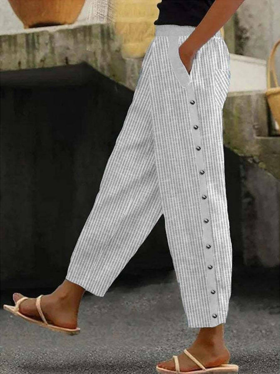 A woman wearing striped pull-on pants with a side button detail and elastic waist.