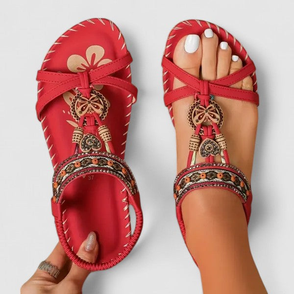 A woman walking comfortably outdoors in cushioned wide-fit orthopaedic sandals with a beaded T-strap and stretch slingback.