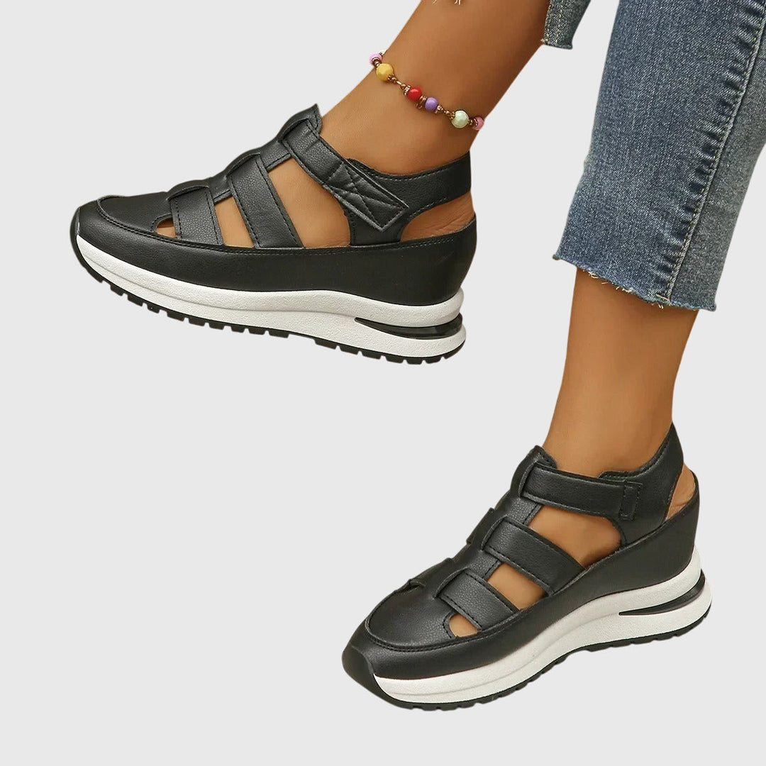 A woman in black cut-out walking sandals exploring a city on a warm day.