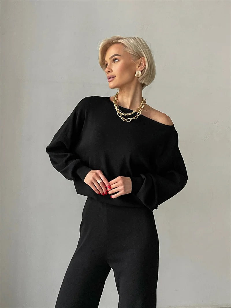 A woman wearing an off-shoulder draped top with wide-leg pants