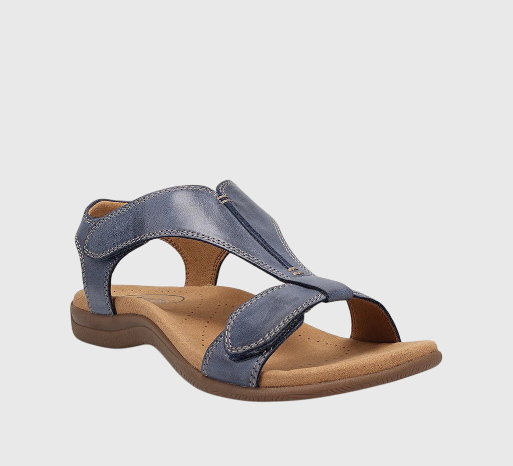 A woman wearing T-strap comfort sandals with a summer dress, looking relaxed and elegant.