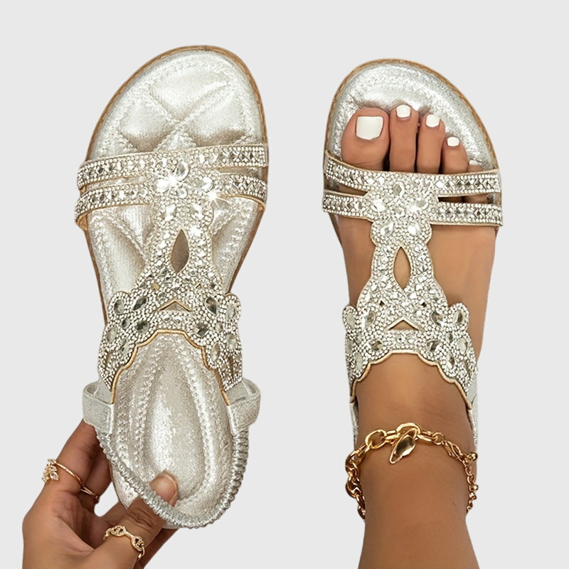 A woman wearing sky blue jewelled sandals with sparkling stones across the straps and a stretchy slingback.