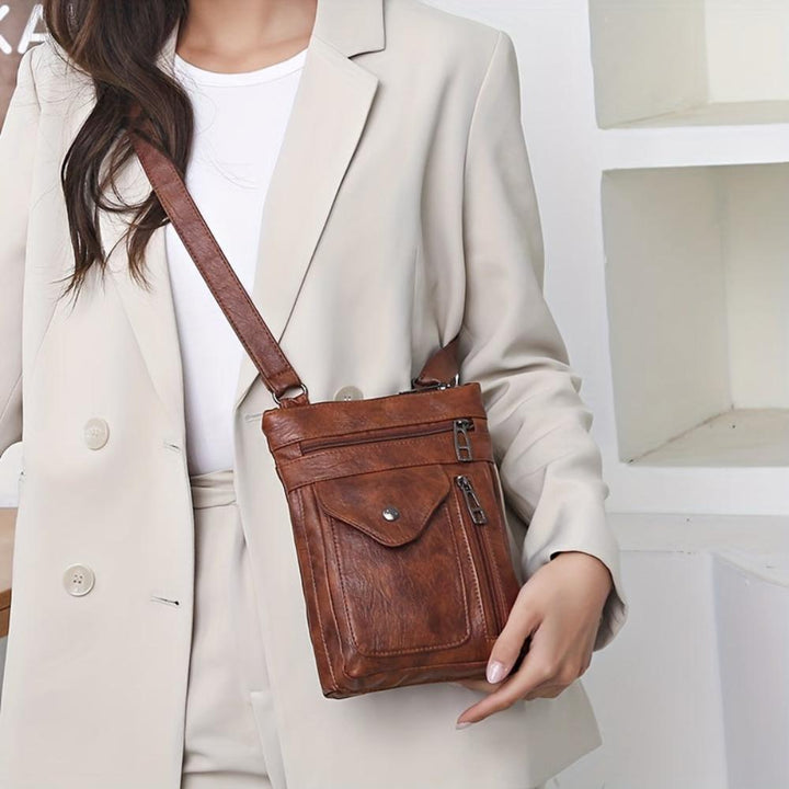 A woman wearing a compact vintage crossbody bag across her body while walking through town.