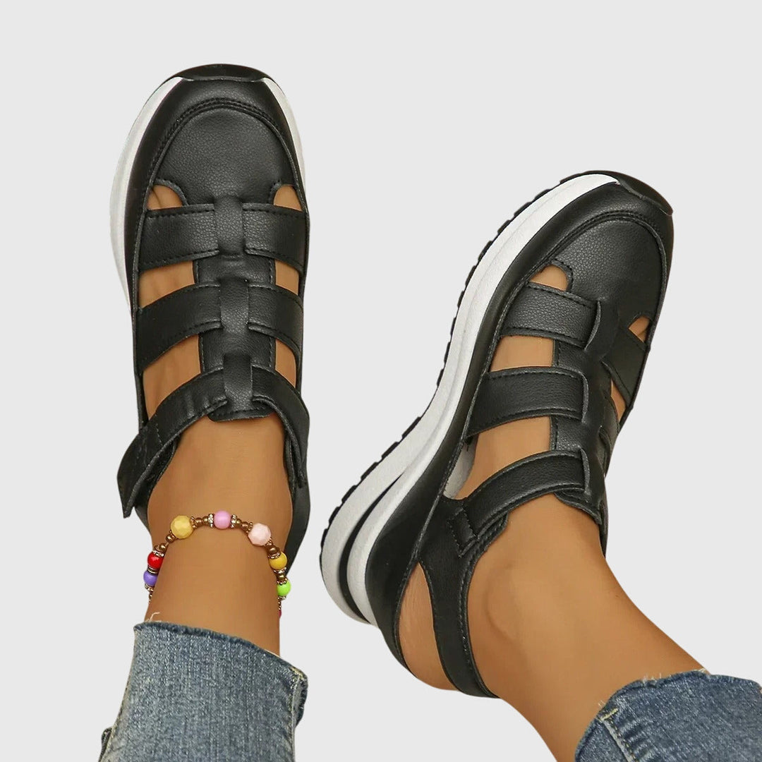 A woman in black cut-out walking sandals exploring a city on a warm day.