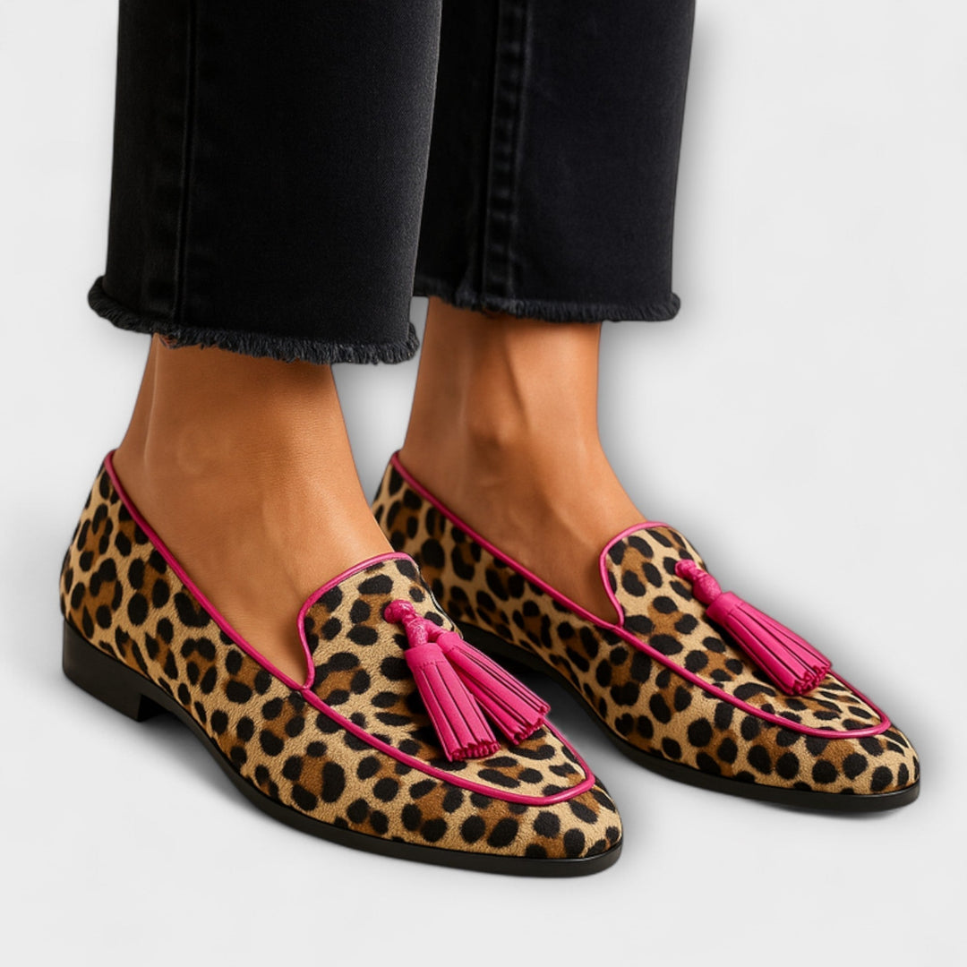 A woman wearing leopard-print loafers with pink tassels on a stylish day out.