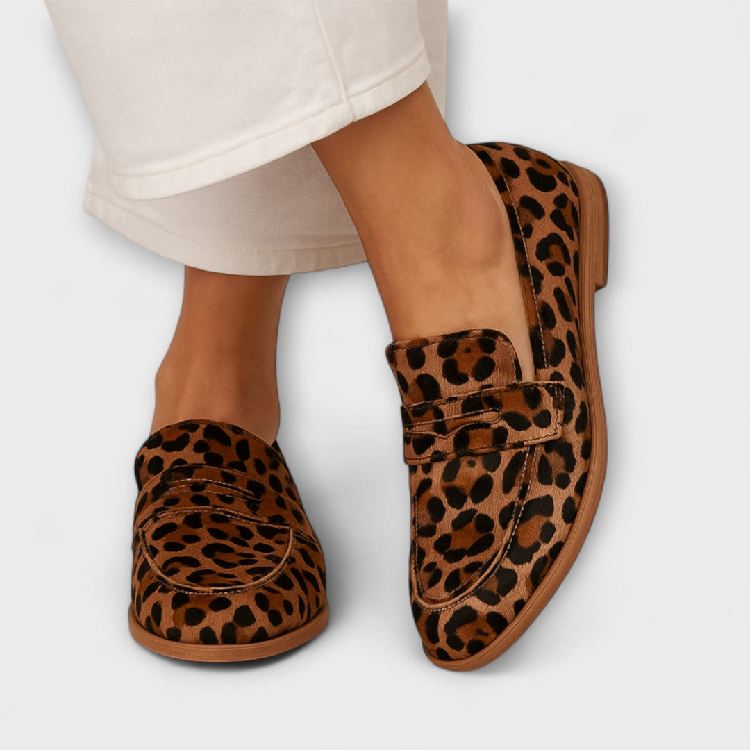 A woman wearing tan leopard print slip-on loafers, styled for a relaxed everyday look.