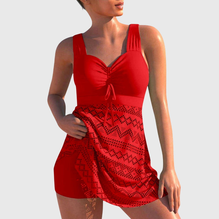A woman by the sea in a printed two-piece swimsuit with a skirted bottom, relaxed and confident.