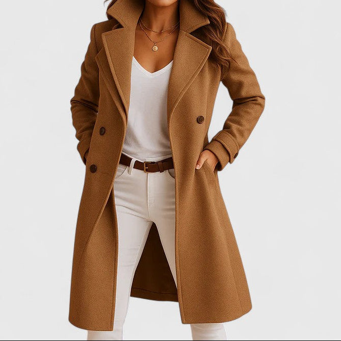 A woman wearing an elegant camel long coat with buttons, styled over jeans and boots in the city.