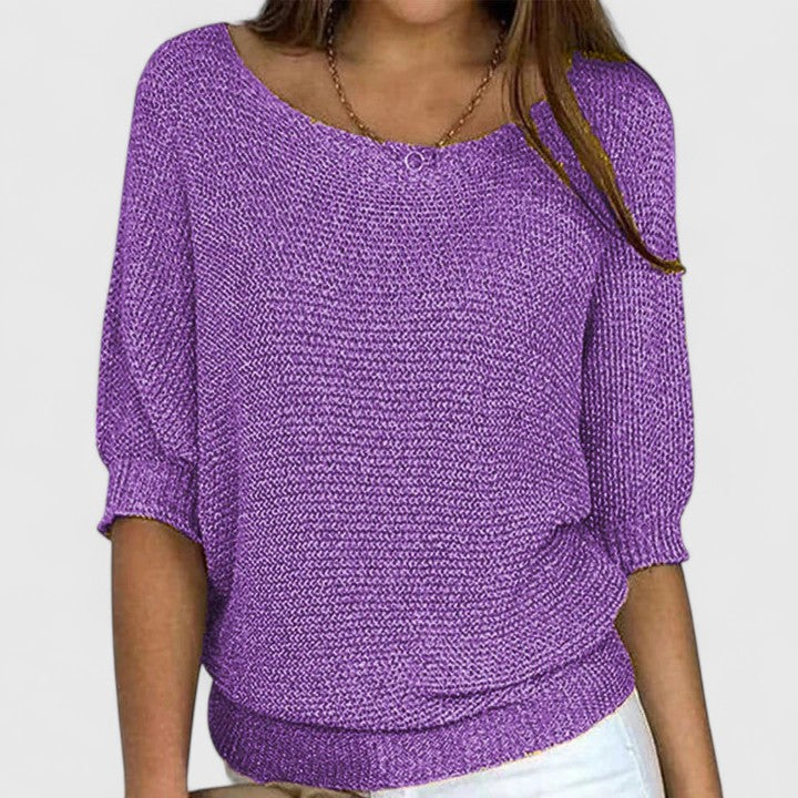 A woman wearing a soft purple sweater with a wide neckline and gently shaped fit.