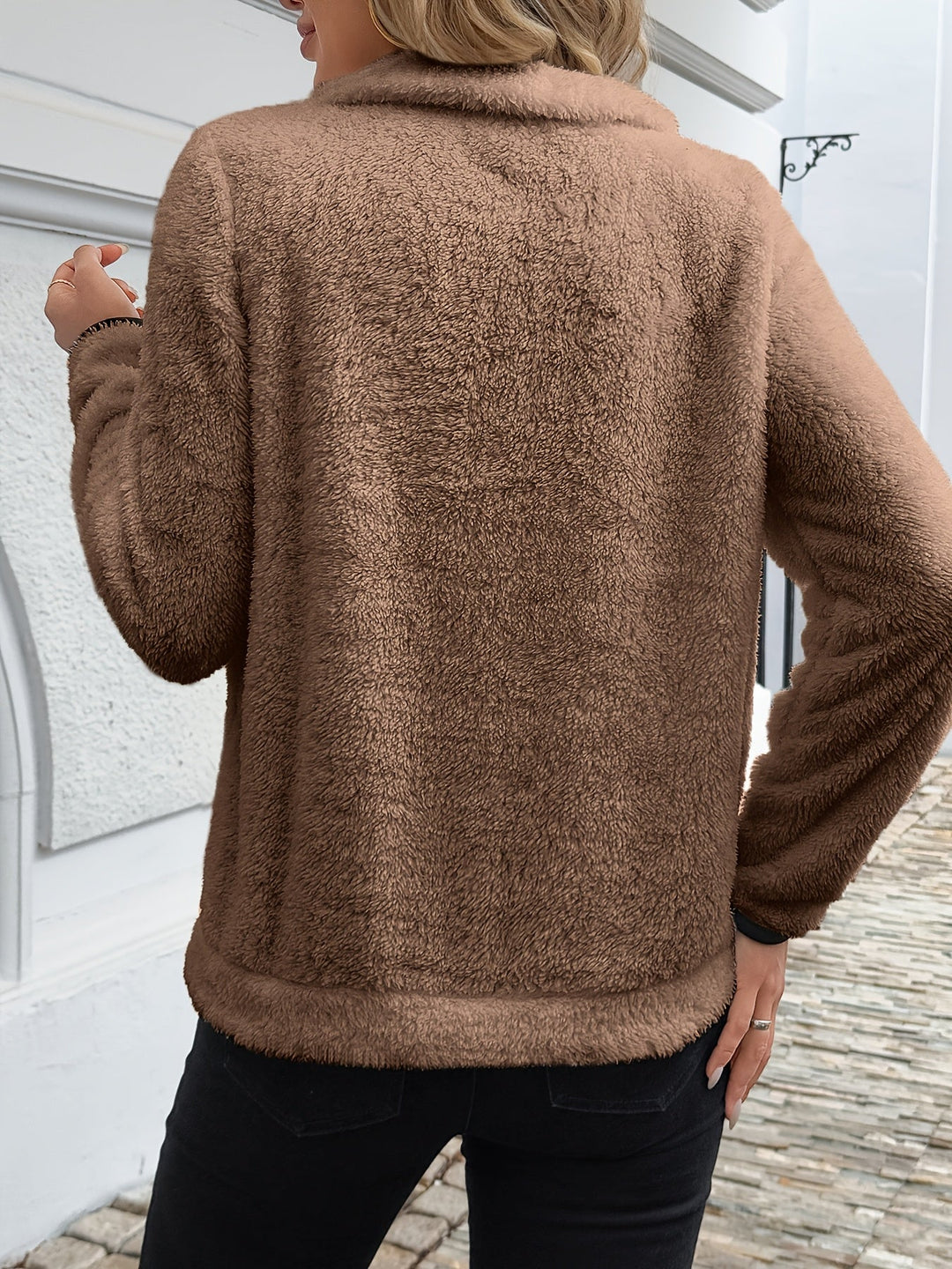 A woman wearing a mid-length zip sweater with a high collar over a roll-neck, relaxed and warm.