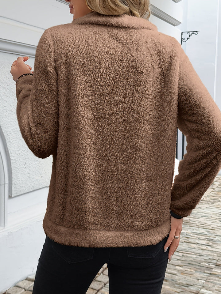 A woman wearing a mid-length zip sweater with a high collar over a roll-neck, relaxed and warm.