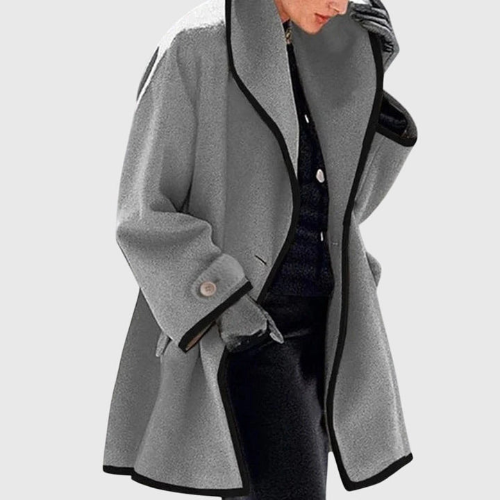 A woman wearing a blue swing-cut jacket with a black contrast trim