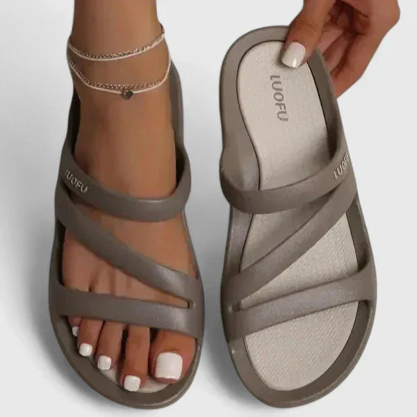 A woman walking confidently outdoors in supportive, cushioned orthopaedic sandals.