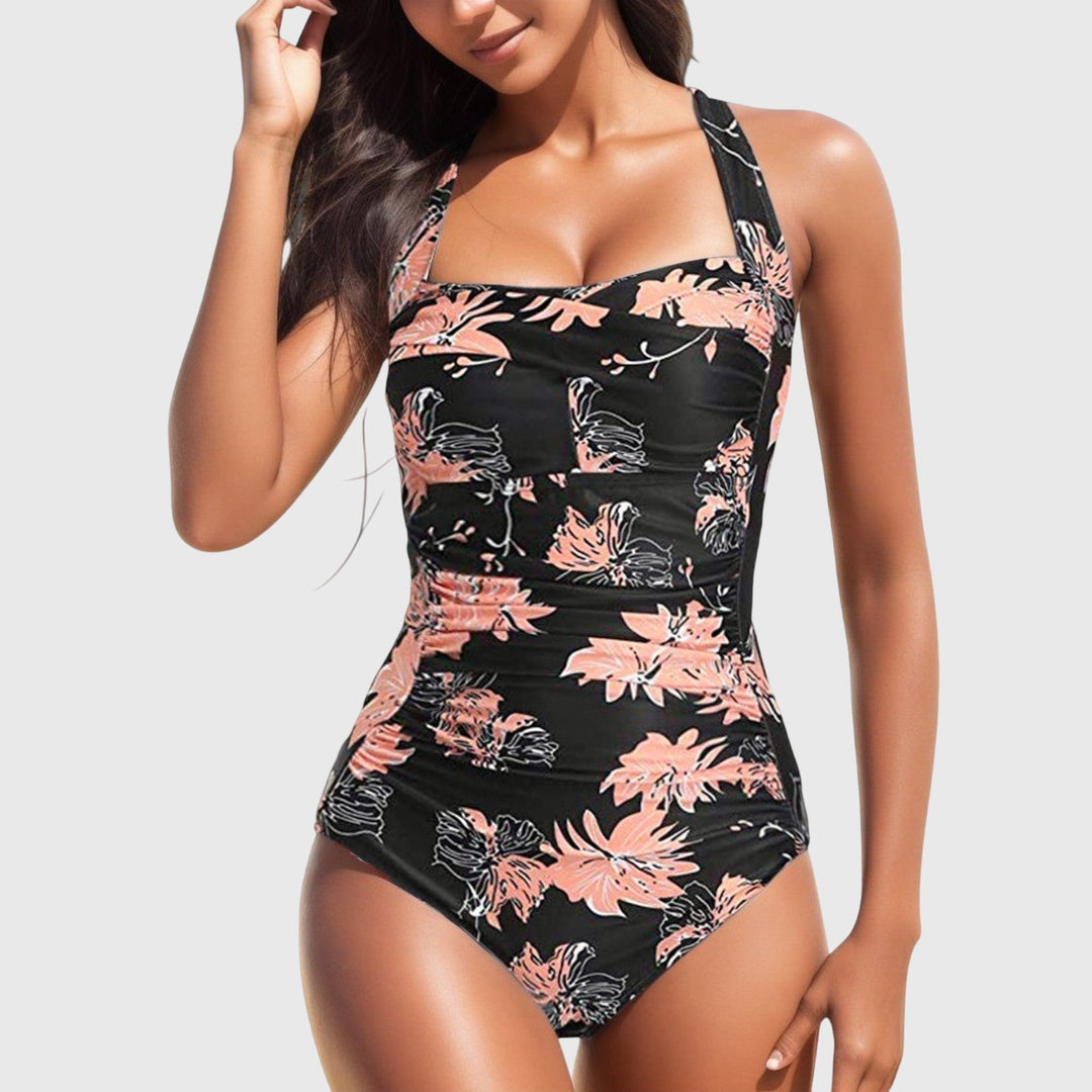 A woman poolside in a patterned one-piece swimsuit, relaxed and confident in the sunshine.