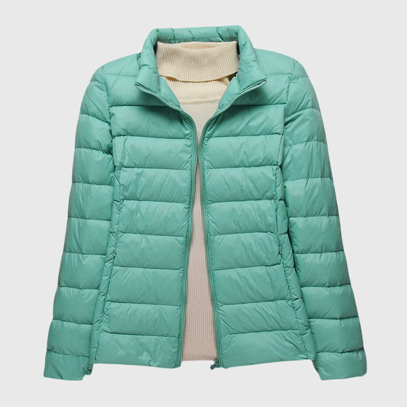 A woman wearing a lightweight padded jacket with a hood, outdoors on a cool day