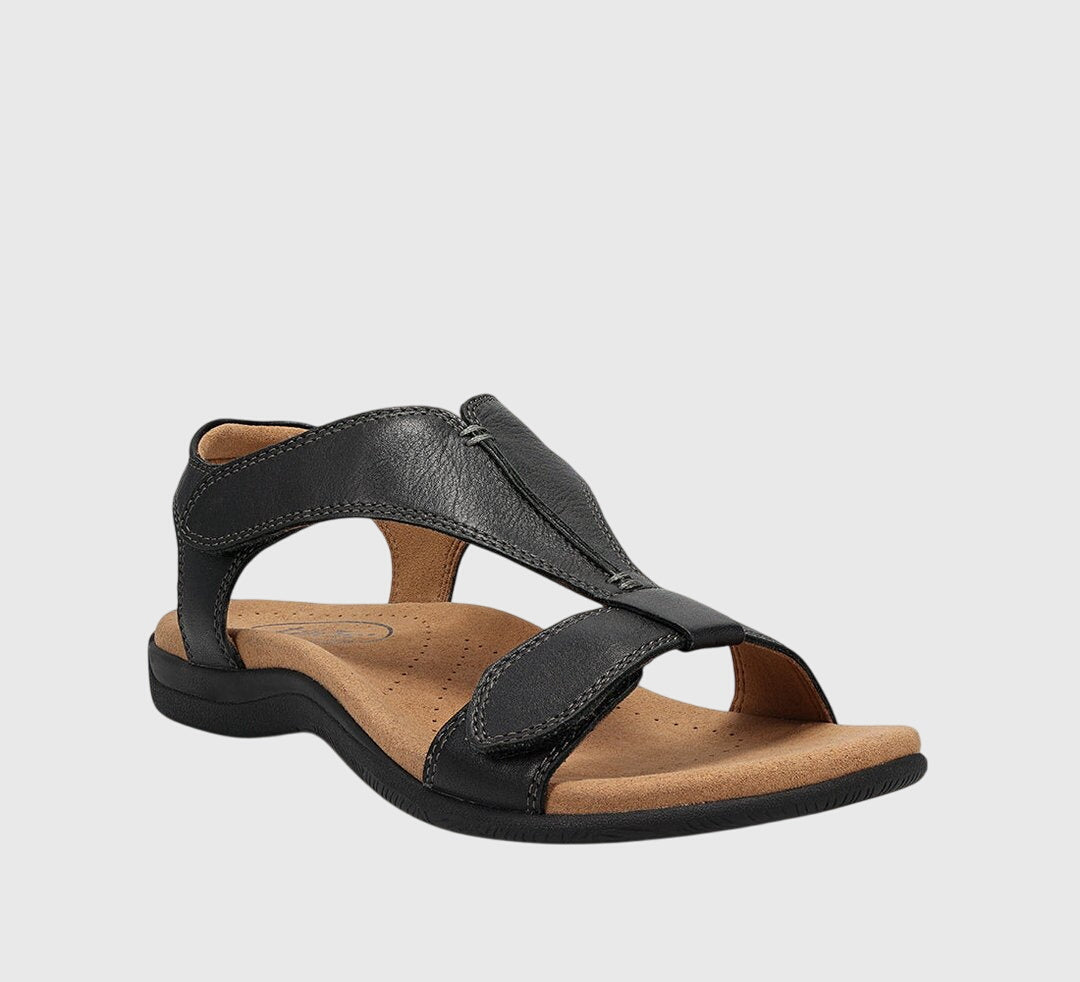 A woman wearing T-strap comfort sandals with a summer dress, looking relaxed and elegant.