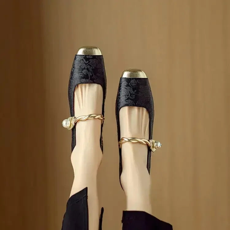 A woman wearing green low-heel Mary Janes with a twisted gold strap, gilded cap toe and a crystal-set heel