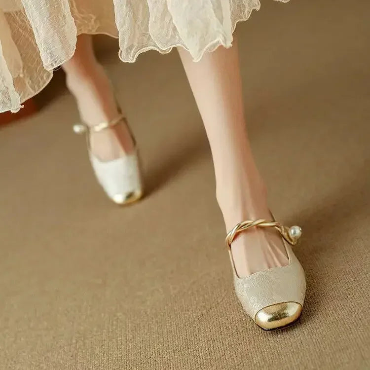 A woman wearing green low-heel Mary Janes with a twisted gold strap, gilded cap toe and a crystal-set heel