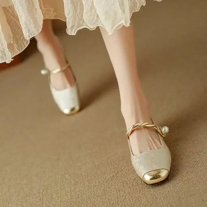 A woman wearing green low-heel Mary Janes with a twisted gold strap, gilded cap toe and a crystal-set heel